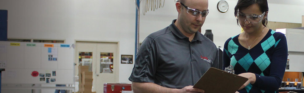 Two people in a warehouse looking at a clipboard.